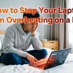 "Concerned man in gray hoodie sitting on bed with laptop showing orange-red glow from keyboard area indicating overheating. Text overlay reads 'How to Stop Your Laptop From Overheating on a Bed'"